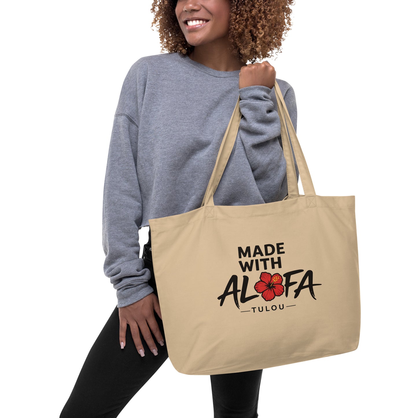 Woman holding a beige tote bag with "Made with Alofa" design on a white background